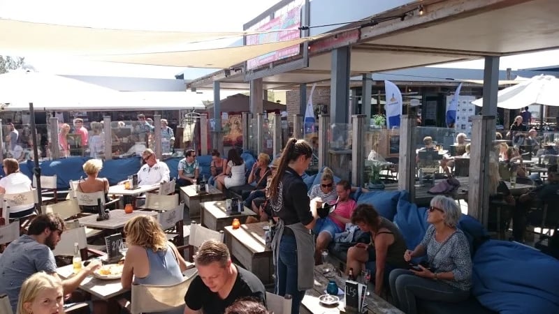 En travl terrasse med blå plokpuder som horekapuder.