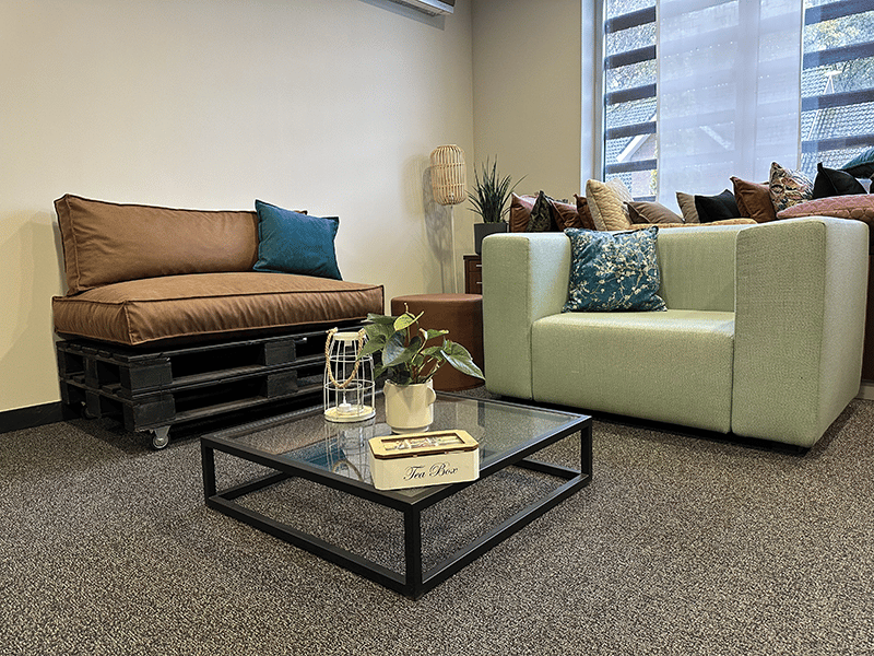 Un palet convertido en un asiento con un cojín para palets en color marrón.