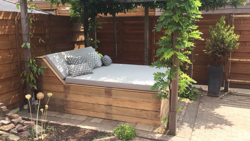 Coussin de transat gris sur un transat en bois dans un jardin.