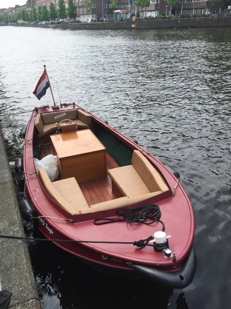 Un bateau rouge avec des coussins sur mesure en beige clair pour le bateau.