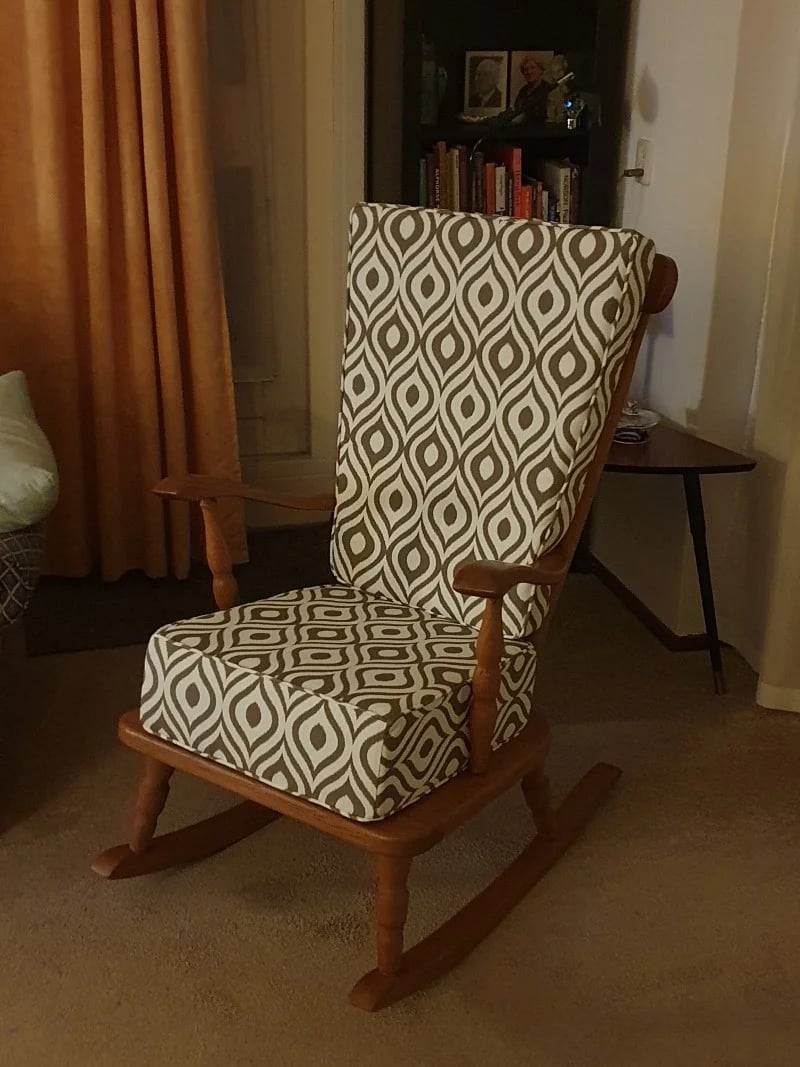 Una silla de madera mecedora con cojines para el asiento y el respaldo.