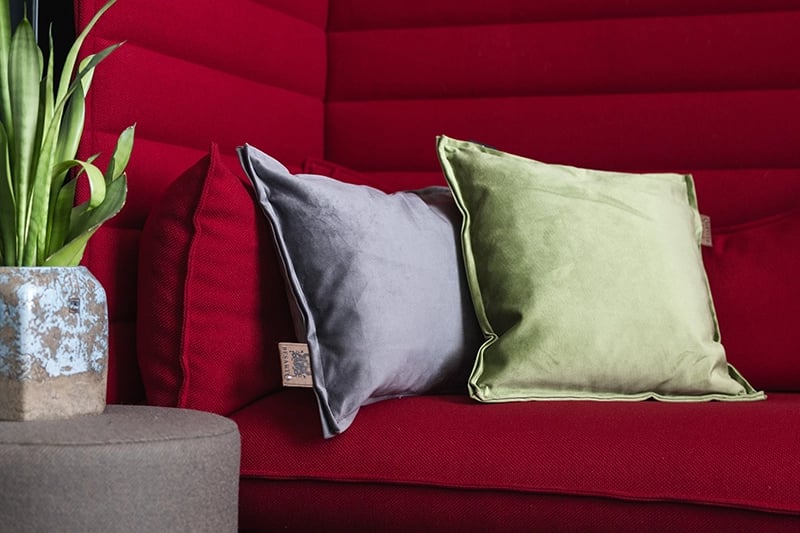 Twee warmtekussens op in het grijs en groen op een rode bank.