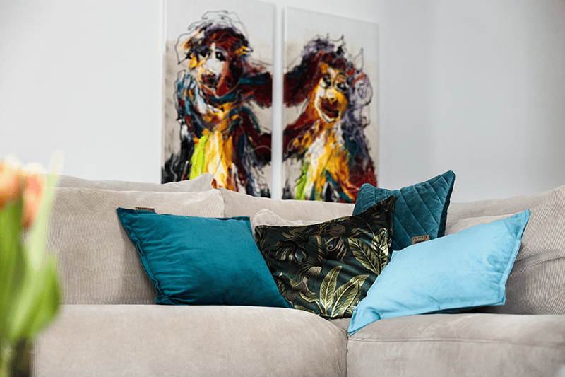 Warmtekussens in verschillende blauwtinten met een portret van honden op de achtergrond.