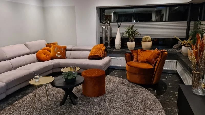 Un salon avec différents sièges, dont un beau pouf orange.