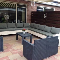 Un conjunto de jardín de madera con cojines para terraza en gris para mayor comodidad.