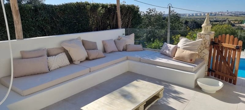 Un banc en béton blanc avec des coussins sur mesure, allant des coussins d'assise aux coussins décoratifs.