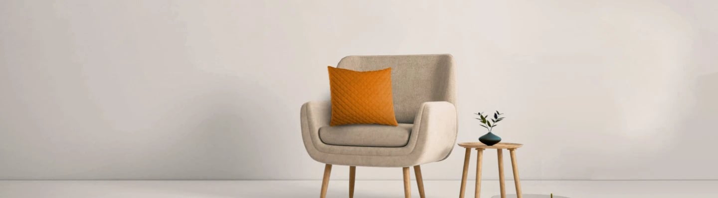  Un coussin décoratif orange avec un motif à carreaux sur une chaise beige clair.